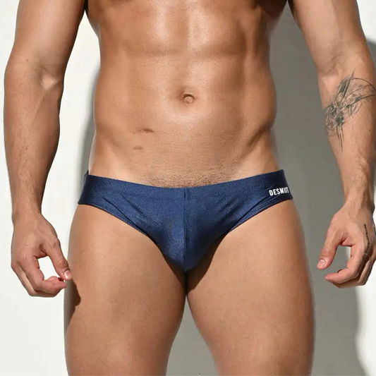 A sexy man in dark blue Desmiit Men’s Bulge Master Low Rise Swim Briefs - pridevoyageshop.com - gay men’s sexy swim briefs, trunks, board shorts, and bikinis
