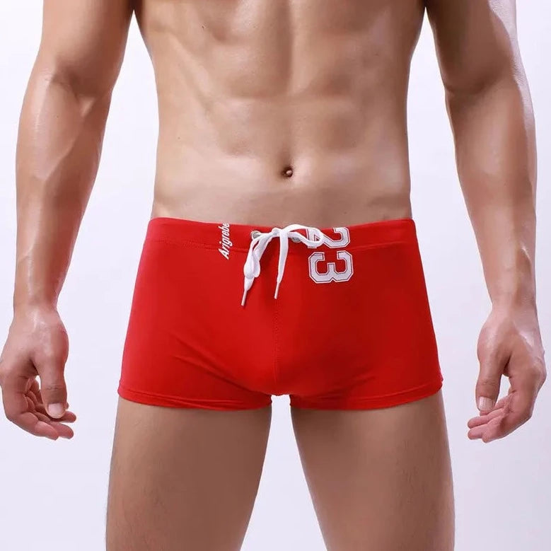 a hot gay man in red Men's 23 Bowtie Swim Trunks - pridevoyageshop.com - gay men’s underwear and swimwear
