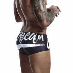a hot gay man in black Alphabet Splash Square Cut Swim Trunks - pridevoyageshop.com - gay men’s underwear and swimwear