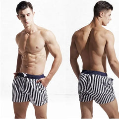a hot gay man in White + Navy Blue Desmiit Vertical Striped Board Shorts - pridevoyageshop.com - gay men’s underwear and swimwear
