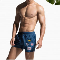 a hot gay man in blue Desmiit Travelers Board Shorts - pridevoyageshop.com - gay men’s underwear and swimwear