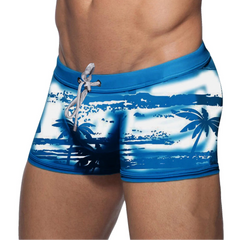 a sexy man in blue Men’s Holiday Hung Swim Trunks- pridevoyageshop.com - gay men’s sexy swim briefs, trunks, board shorts, and bikinis
