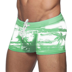 a sexy man in green Men’s Holiday Hung Swim Trunks- pridevoyageshop.com - gay men’s sexy swim briefs, trunks, board shorts, and bikinis