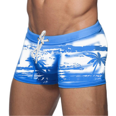a sexy man in sky blue Men’s Holiday Hung Swim Trunks- pridevoyageshop.com - gay men’s sexy swim briefs, trunks, board shorts, and bikinis