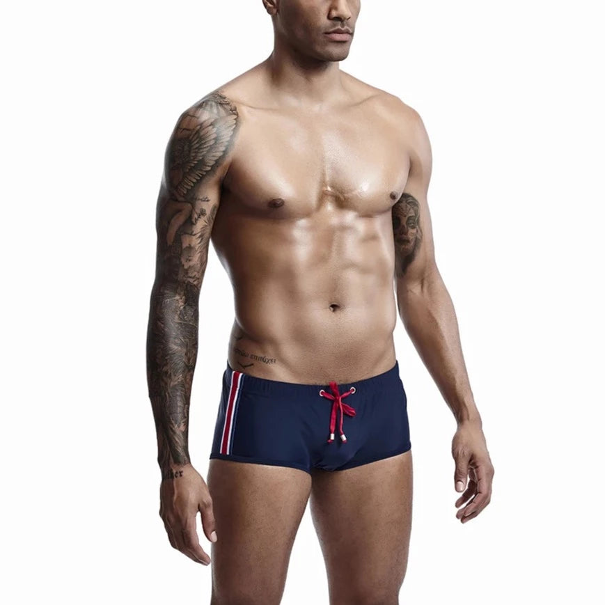 a hot gay man in navy Bold Stripe Swim Trunks - pridevoyageshop.com - gay men’s underwear and swimwear