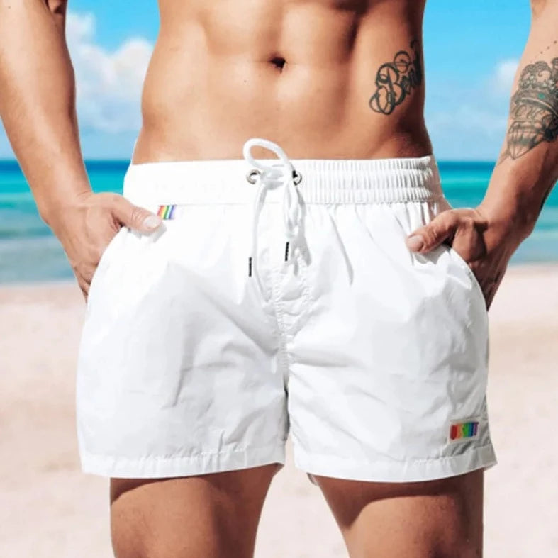 a hot gay man in white Desmiit Rainbow Pride Pocket Board Shorts - pridevoyageshop.com - gay men’s underwear and swimwear