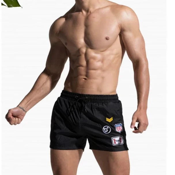 a hot gay man in black Desmiit Travelers Board Shorts - pridevoyageshop.com - gay men’s underwear and swimwear