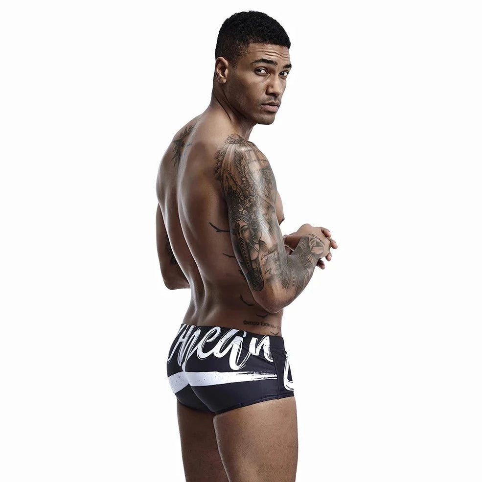 a hot gay man in black Alphabet Splash Square Cut Swim Trunks - pridevoyageshop.com - gay men’s underwear and swimwear