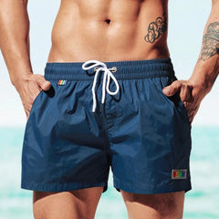 a hot gay man in blue Desmiit Rainbow Pride Pocket Board Shorts - pridevoyageshop.com - gay men’s underwear and swimwear
