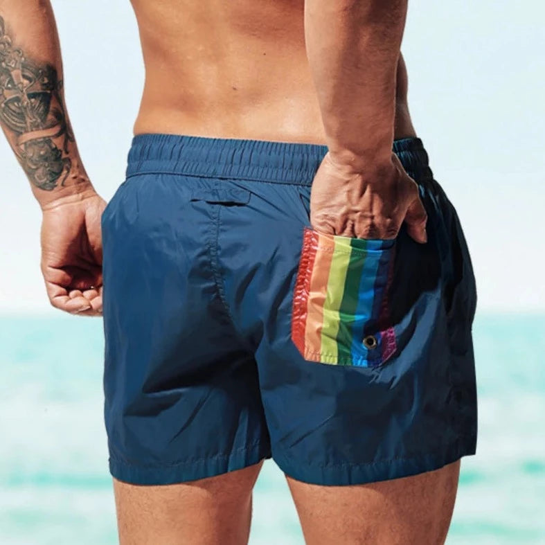 a hot gay man in blue Desmiit Rainbow Pride Pocket Board Shorts - pridevoyageshop.com - gay men’s underwear and swimwear