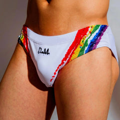 a sexy gay man in white DM Rainbow Splash Swim Briefs - pridevoyageshop.com - gay men’s underwear and swimwear