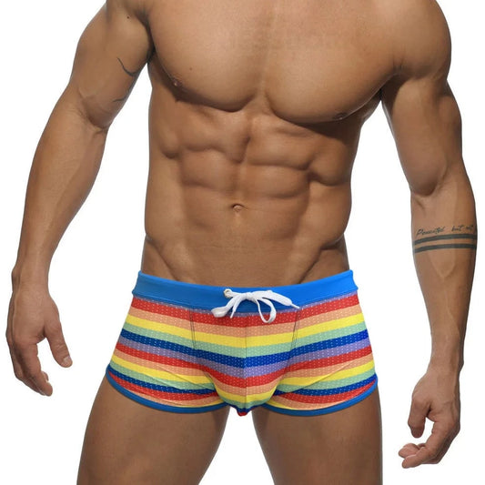 a hot gay man in Rainbow Striped Mesh Square Cut Swim Trunks - pridevoyageshop.com - gay men’s underwear and swimwear
