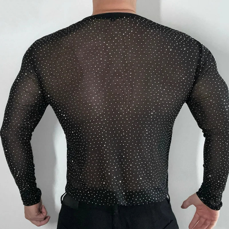 Twinkle Twunk Mesh Long Sleeve Black color sheer sparkle mesh long sleeve top worn by a muscular gay man posing in studio lighting pridevoyageshopcom gay mens gym tank tops mesh tank tops clubwear fashion tops and activewear