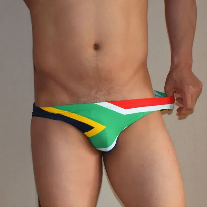 a sexy man in South Africa flag Men’s Flag Frenzy Swim Briefs - pridevoyageshop.com - gay men’s sexy swim briefs, trunks, board shorts, and bikinis