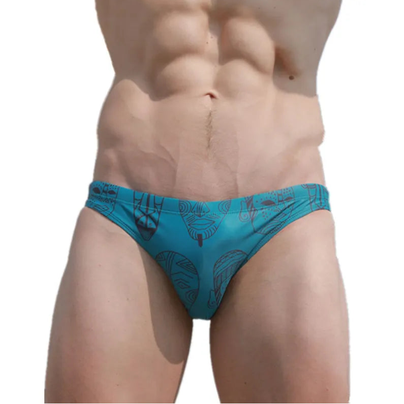 a sexy man in Teal Totem Men’s Poolside Rites Swim Briefs - pridevoyageshop.com - gay men’s sexy swim briefs, trunks, board shorts, and bikinis