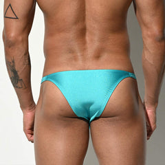 a sexy man in aqua Desmiit Men’s Risk It All Half Hip Shiny Micro Swim Bikini - pridevoyageshop.com - gay men’s sexy swim briefs, trunks, board shorts, and bikinis