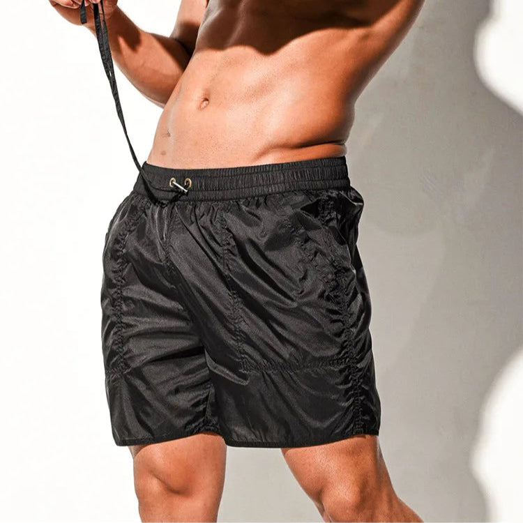 a sexy man in black Men’s Cellblock Sheen Swim Short – pridevoyageshop.com – gay men’s sexy swim briefs, trunks, board shorts, and bikinis
