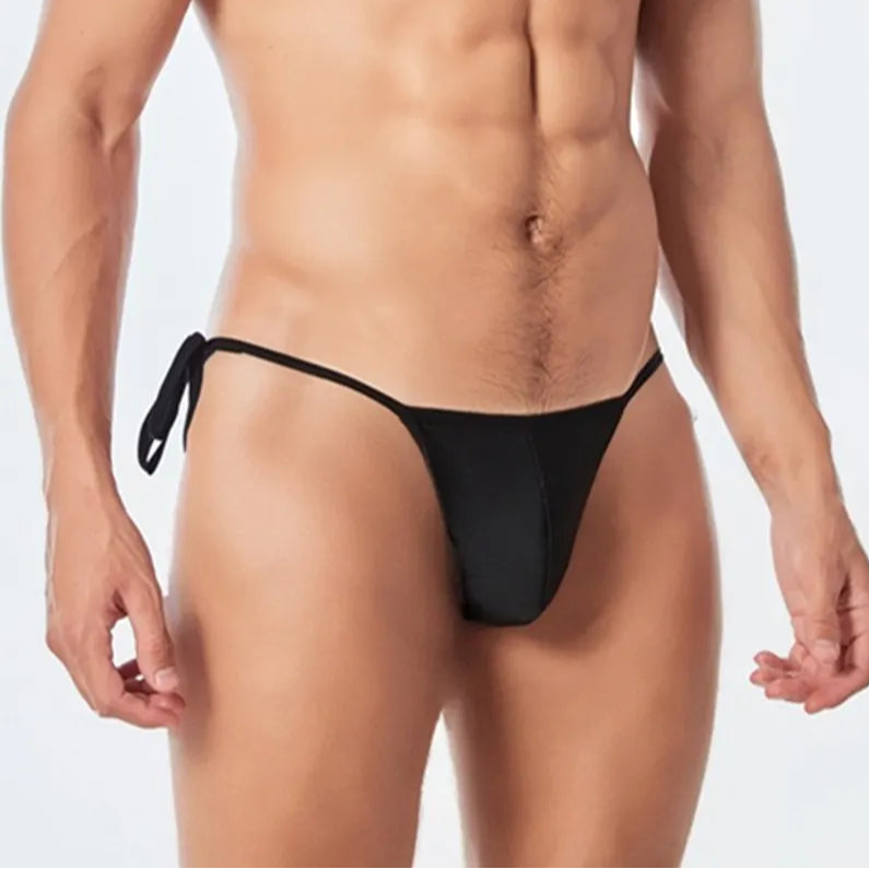 a sexy man in black Men’s Werk It Tie-Up Swim Bikini Thong – pridevoyageshop.com – gay men’s sexy swim briefs, trunks, board shorts, and bikinis
