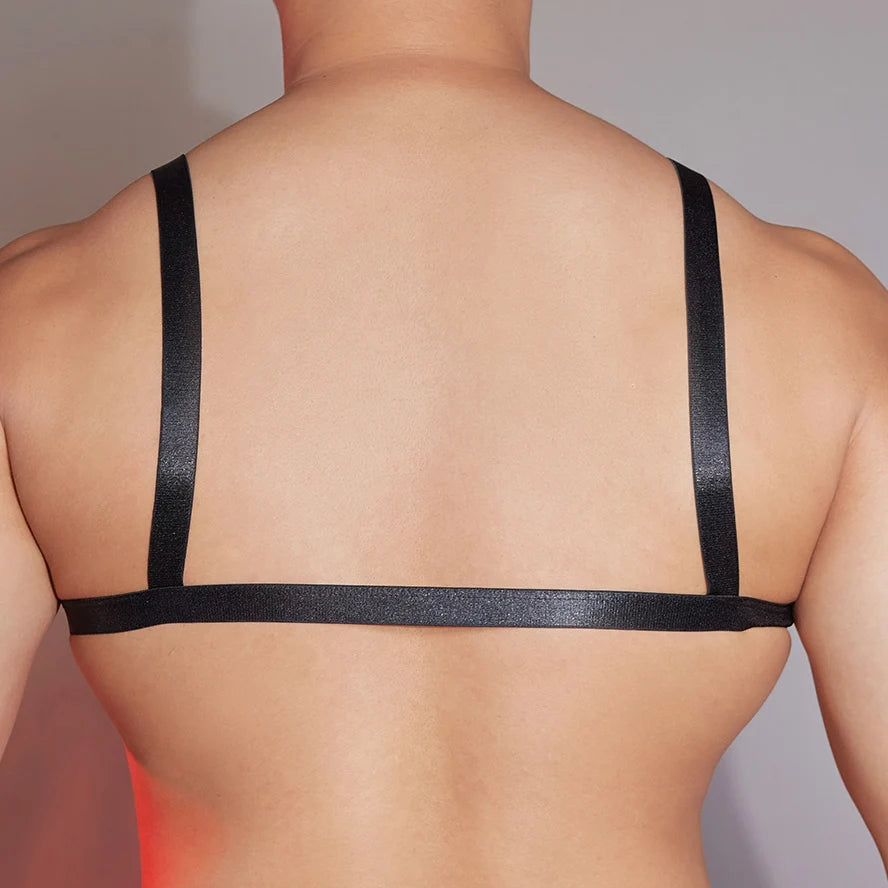 a sexy man in black faux-leather bralette with front clasp, shiny finish hugging chest and showing pecs and straps – pridevoyageshop.com – gay men’s harness, lingerie and fetish wear