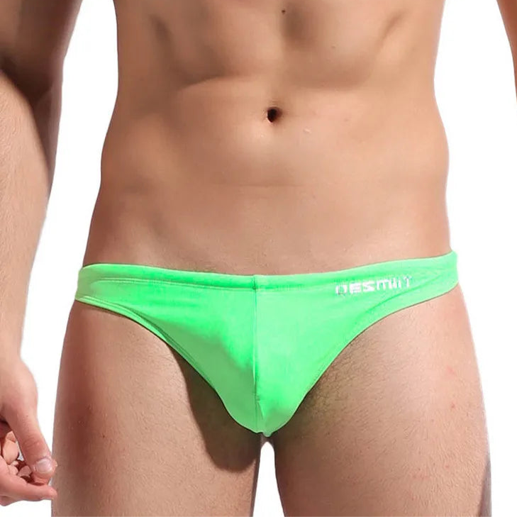 a sexy man in bright green DESMIIT Men’s Candy Drop Micro Bikini Swim Briefs - pridevoyageshop.com - gay men’s sexy swim briefs, trunks, board shorts, and bikinis
