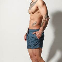 a sexy man in dark blue Desmiit Men’s Circuit Signal Swim Short – pridevoyageshop.com – gay men’s sexy swim briefs, trunks, board shorts, and bikinis