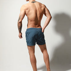 a sexy man in dark blue Desmiit Men’s Circuit Signal Swim Short – pridevoyageshop.com – gay men’s sexy swim briefs, trunks, board shorts, and bikinis