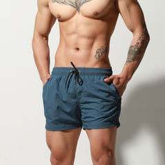 a sexy man in dark blue Desmiit Men’s Circuit Signal Swim Short – pridevoyageshop.com – gay men’s sexy swim briefs, trunks, board shorts, and bikinis