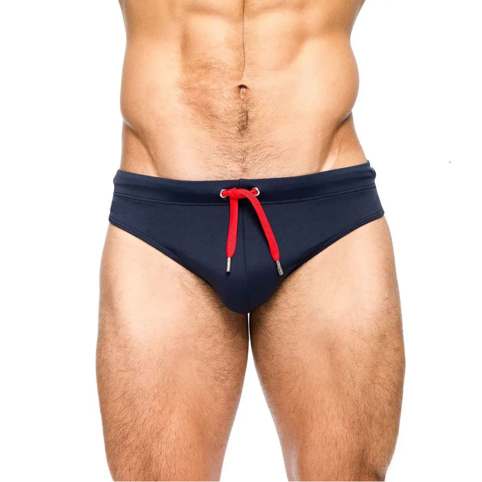 a sexy man in dark blue Men’s Beach Brat Swim Briefs - pridevoyageshop.com - gay men’s sexy swim briefs, trunks, board shorts, and bikinis