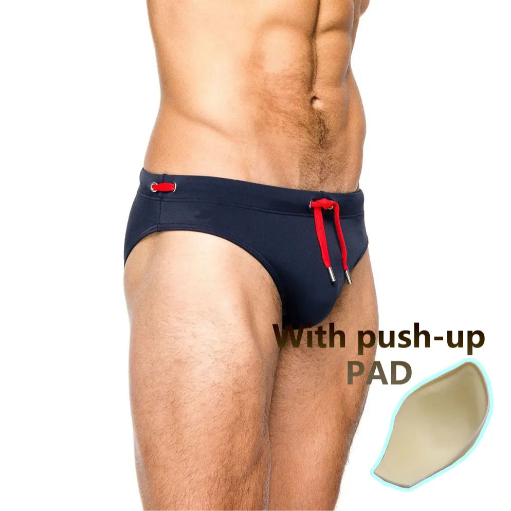 a sexy man in dark blue Men’s Beach Brat Swim Briefs with pad - pridevoyageshop.com - gay men’s sexy swim briefs, trunks, board shorts, and bikinis