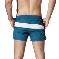 a sexy man in dark blue Men’s Block Party Volley Swim Short – pridevoyageshop.com – gay men’s sexy swim briefs, trunks, board shorts, and bikinis