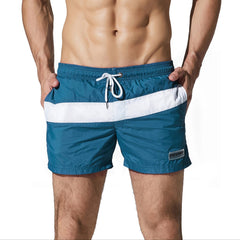 a sexy man in dark blue Men’s Block Party Volley Swim Short – pridevoyageshop.com – gay men’s sexy swim briefs, trunks, board shorts, and bikinis