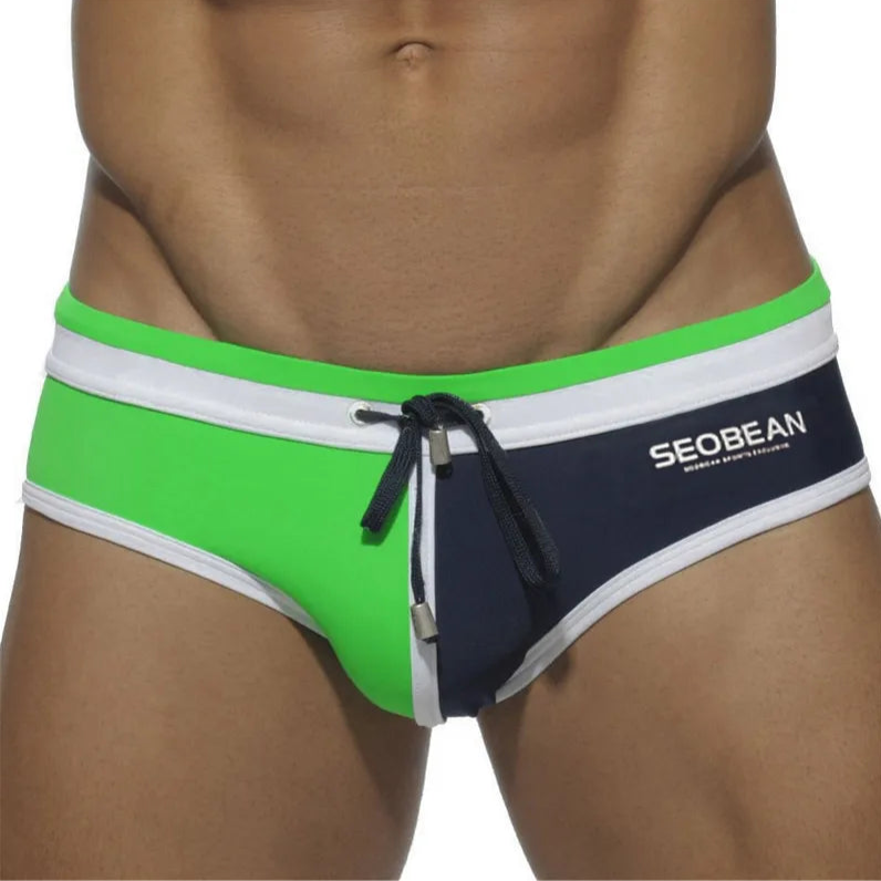 a sexy man in green and dark blue Men’s Split Decision Bulge Swim Briefs - pridevoyageshop.com - gay men’s sexy swim briefs, trunks, board shorts, and bikinis