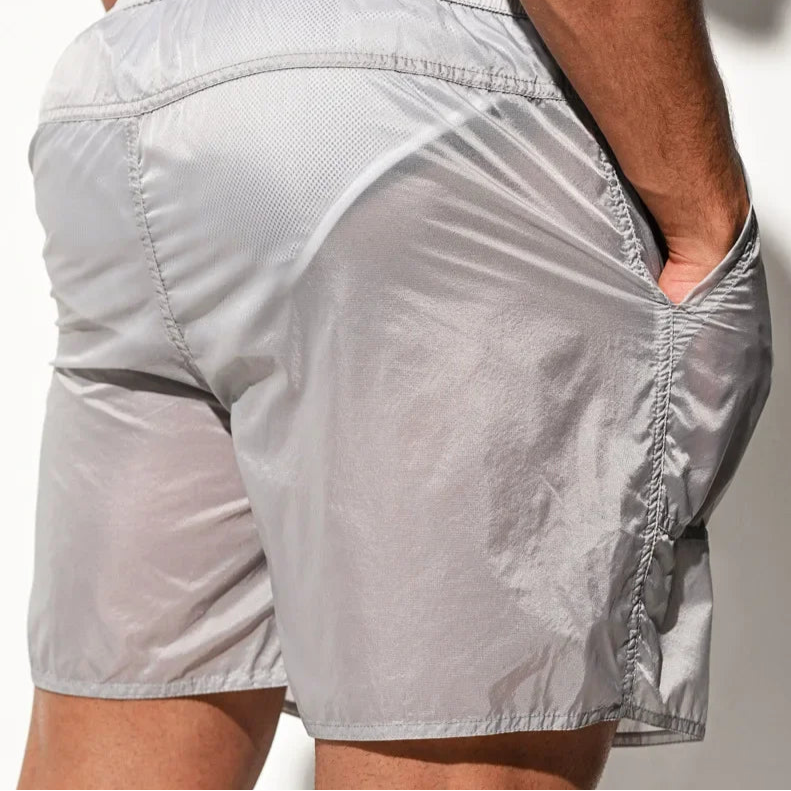 a sexy man in light gray Men’s Cellblock Sheen Swim Short – pridevoyageshop.com – gay men’s sexy swim briefs, trunks, board shorts, and bikinis