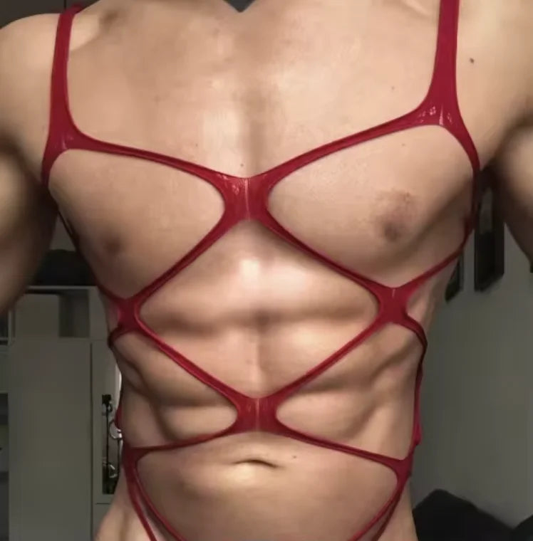 a sexy man in red web-mesh bodysuit, revealing torso, high-cut leg and sultry mesh straps – pridevoyageshop.com – gay men’s harness, lingerie and fetish wear
